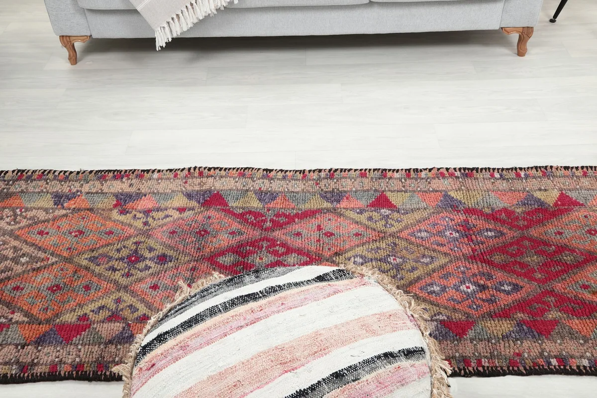View down the length of the runner rug, with a decorative pouf in the foreground