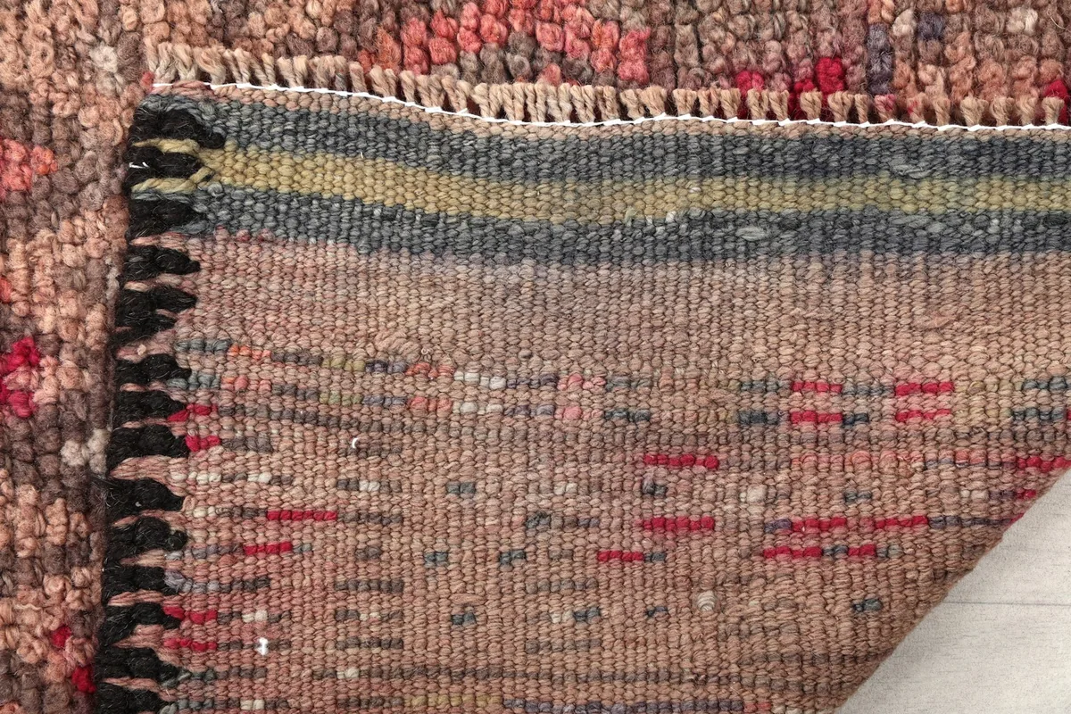Close-up of the rug's back, revealing the tight weave of the cotton foundation and colored threads