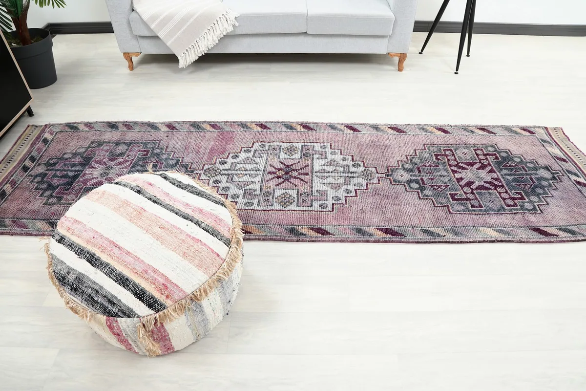 Full length view of the runner rug in a room with a pouf, illustrating its scale.