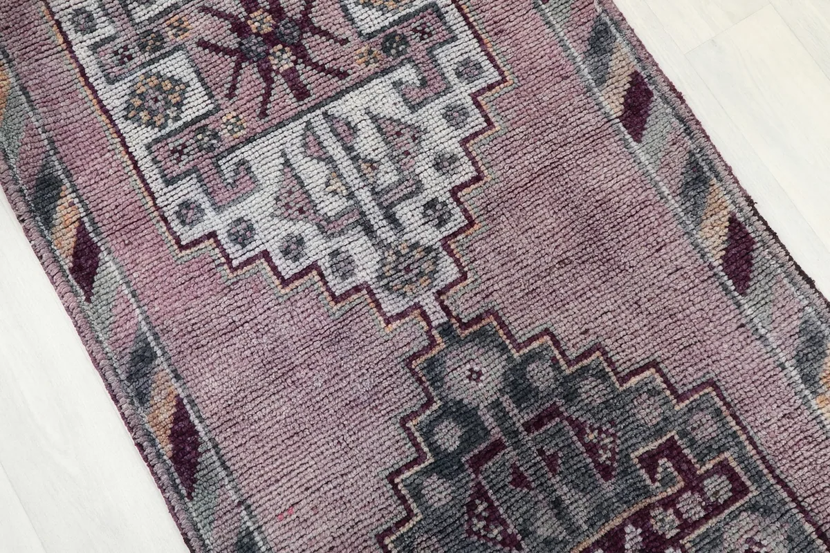 Angled close-up of the rug's central design, revealing the rose and gray tribal patterns.