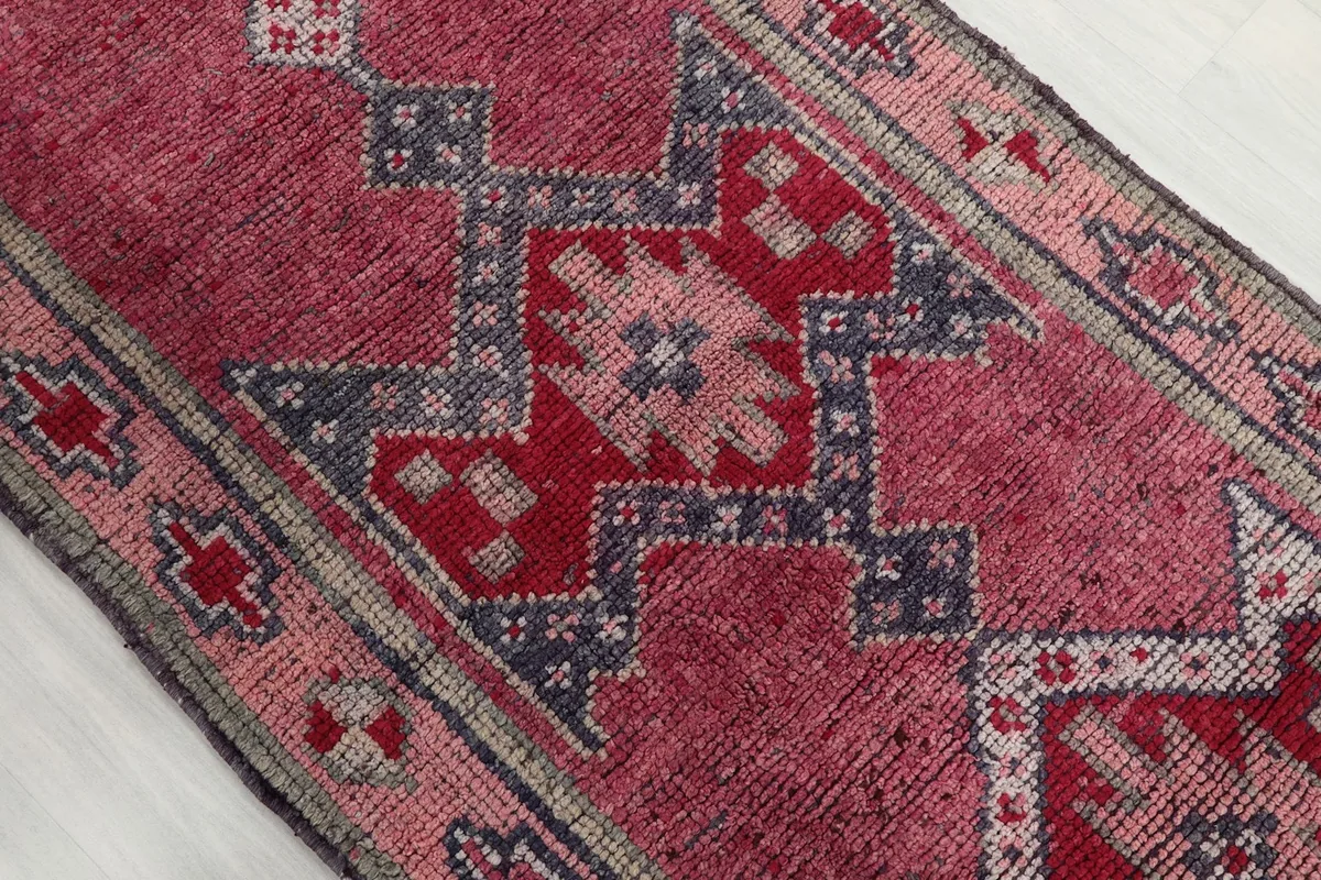 Close-up of the rose field and navy geometric motifs on the hand-knotted rug.