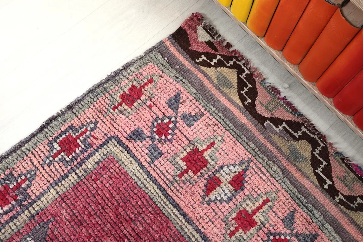 Close-up of the rug's end, showing the border, fringe, and a slight discoloration.
