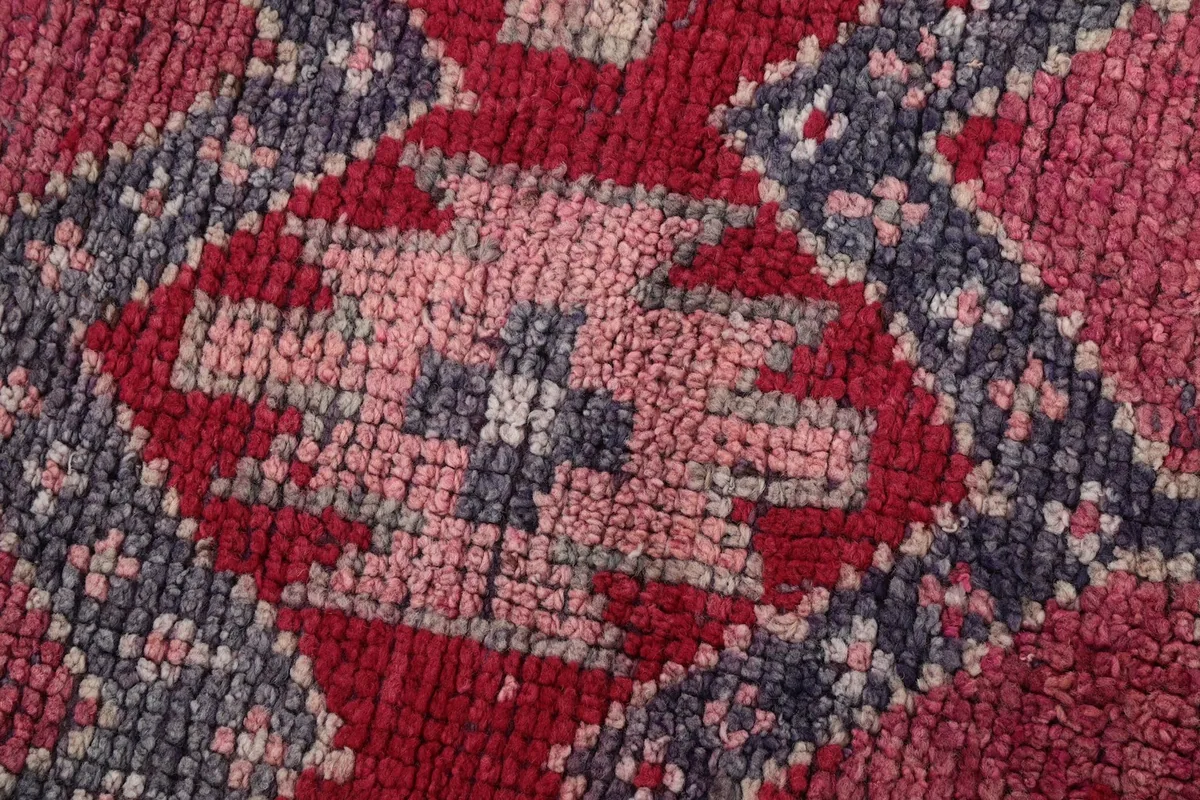 Macro view of the wool pile texture and color variations in the rug's central design.
