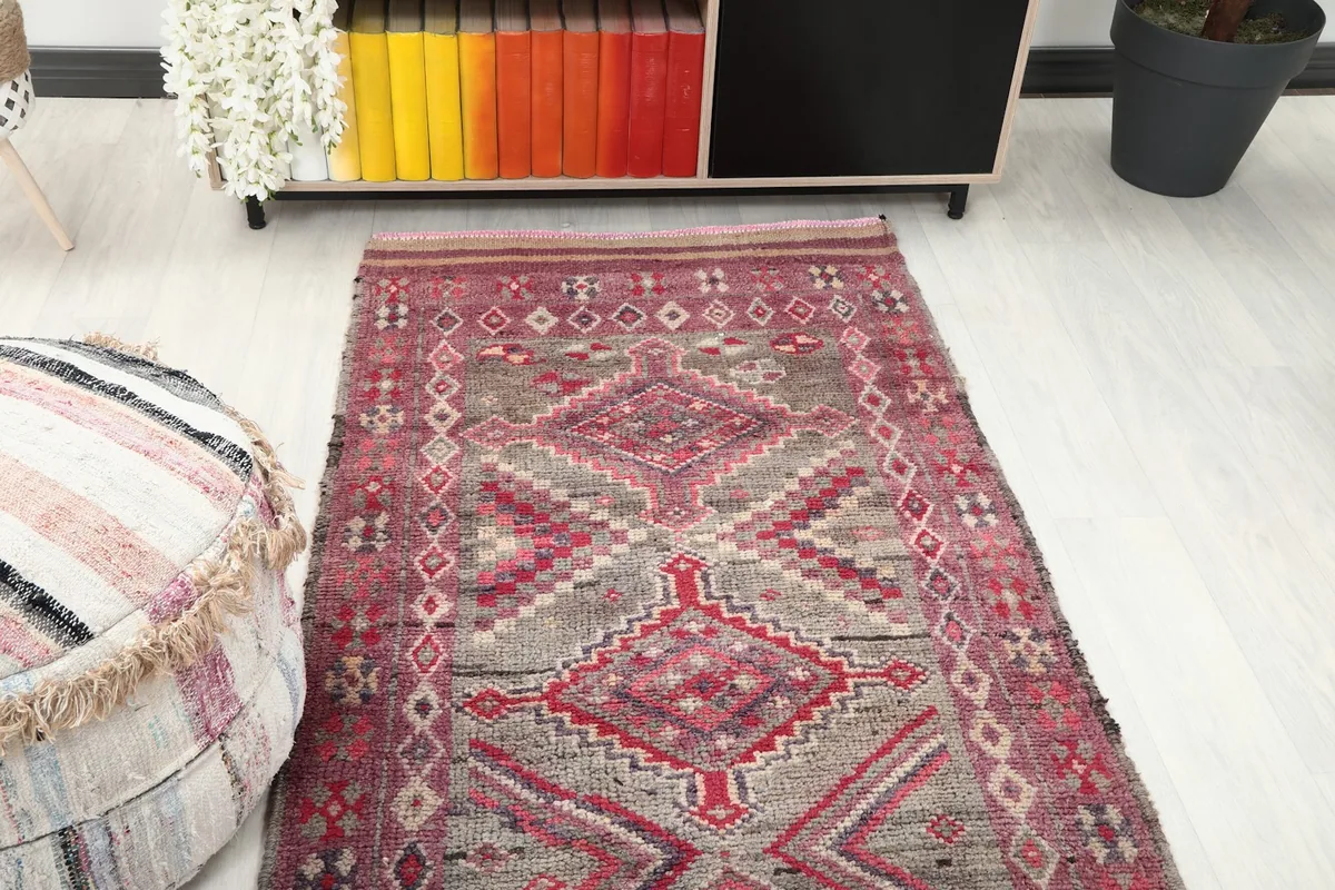 Partial room view focusing on the runner rug's pattern near a pouf and cabinet