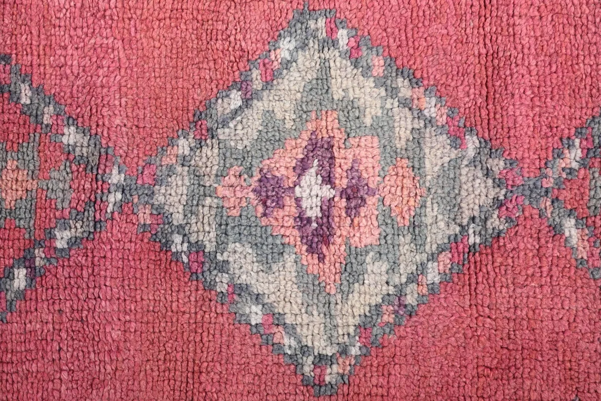 Detailed view of a single geometric diamond motif with intricate patterns in gray, purple, and rose.