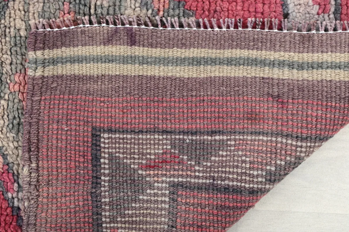 Close-up of the rug's end, showing the woven stripes of the foundation and the short, durable fringe.