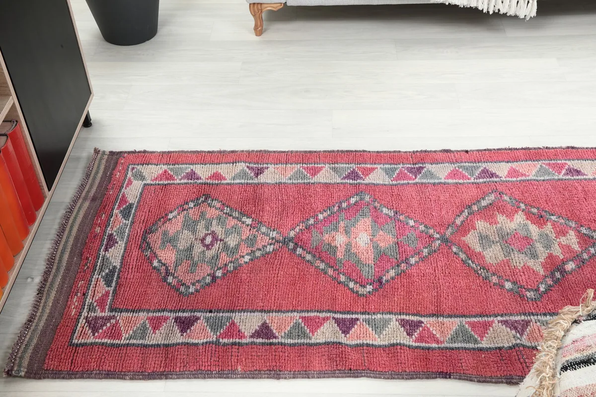 Overhead shot showing a section of the rose runner rug with multiple geometric diamonds, leading towards a sofa.