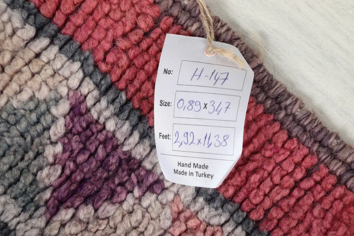 A close-up of the rug's texture and a tag showing the dimensions in metric and imperial measurements.