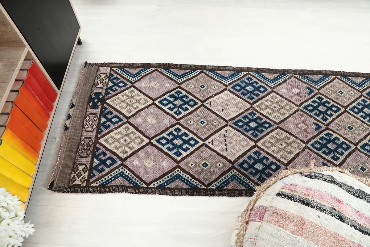 View of the runner rug extending across a room, with a pouf in the foreground