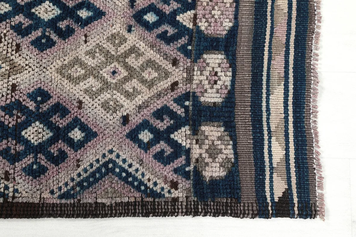 Detailed view of the intricate geometric motifs and border design at one end of the rug