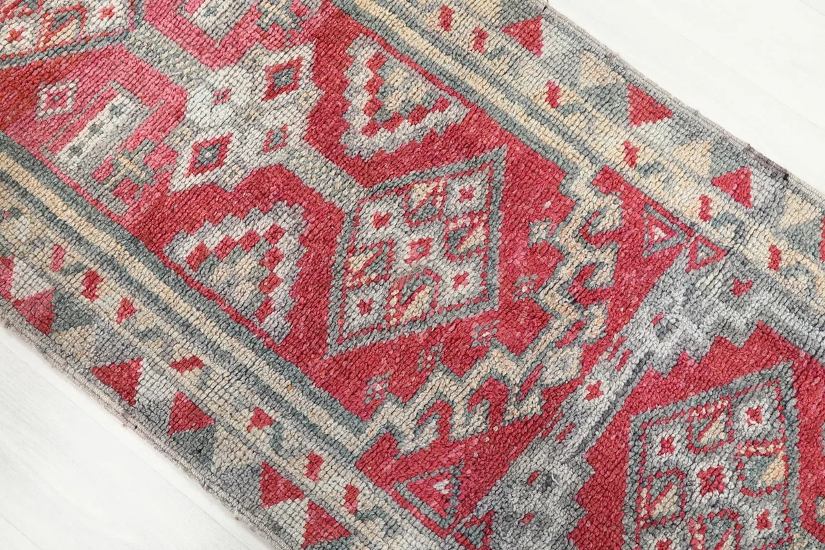 Close-up of the geometric motifs and color blending within the red and gray sections of the rug.