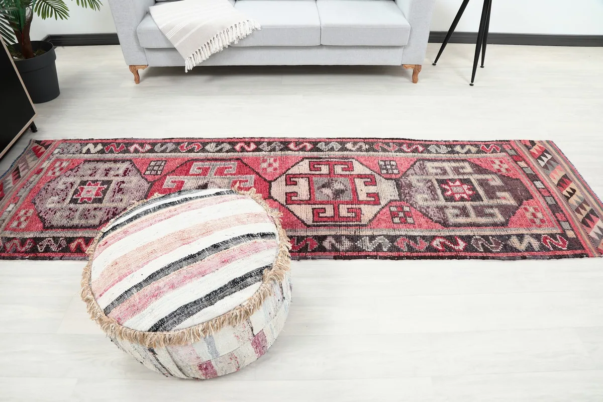 Full length view of the runner rug in a room, with a decorative pouf in the foreground
