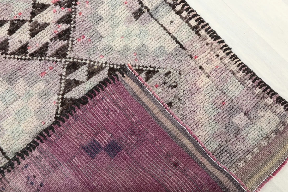 Corner of the runner rug flipped to show the back of the hand-knotted foundation