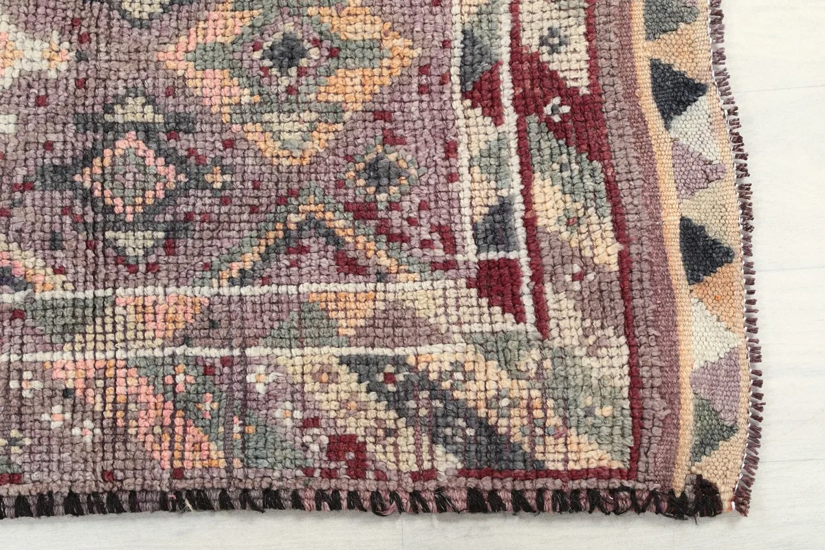 Detailed view of the rug's border and corner, showcasing the hand-knotted wool pile and color variations.