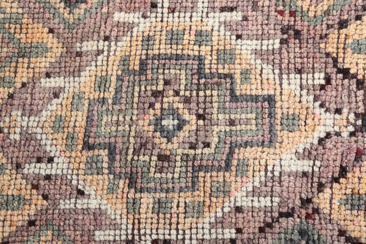 Macro detail of the rug's central medallion-like geometric design and individual knot texture.