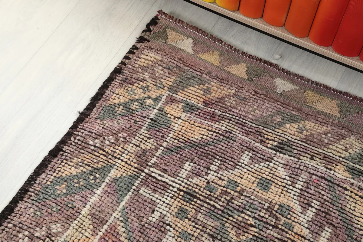 View along the side border of the rug, showing the tribal-inspired patterns and fringe details.