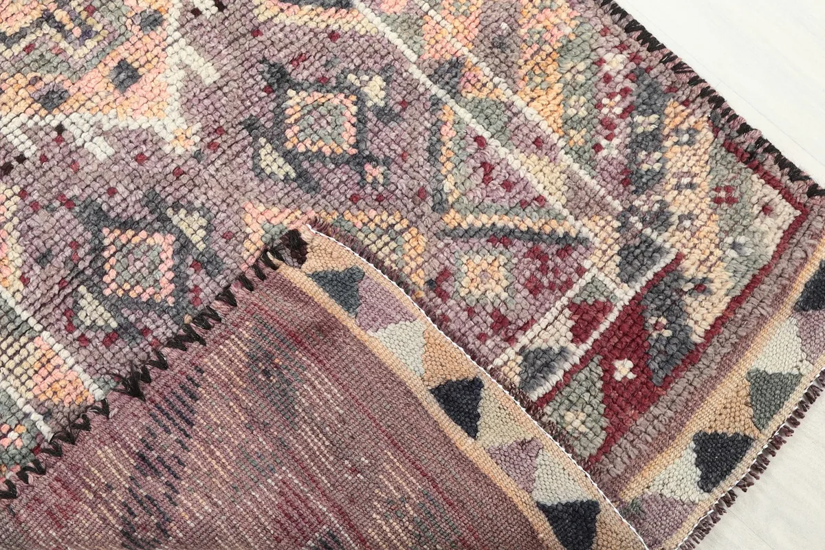 Close-up of the rug's backside, revealing the cotton foundation and the reverse of the hand-knotted wool pile.