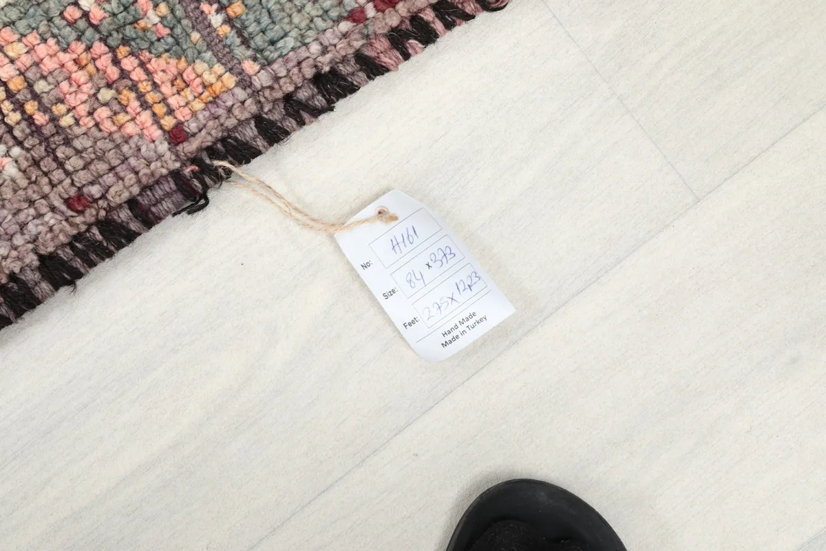 Photo of the rug's product tag with size and material information, next to a foot for scale.
