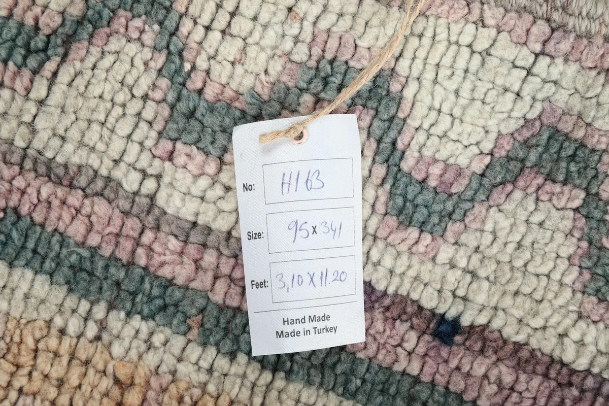 Tag showing the rug's dimensions and origin, placed on the wool pile