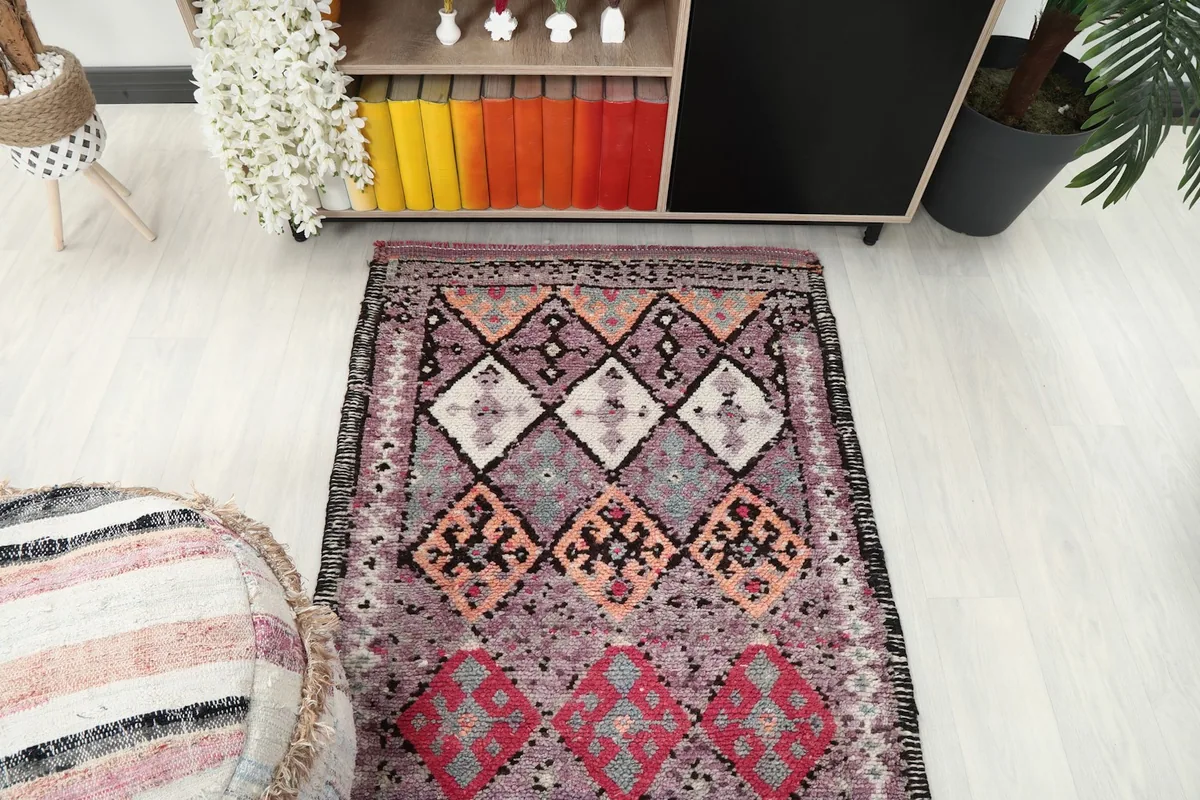 Overhead shot of the runner rug's pattern from one end, positioned in a room with an ottoman and furniture.