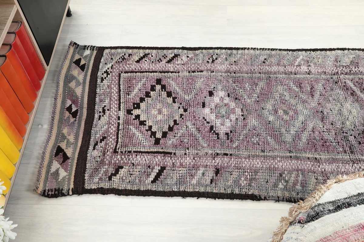 Angle shot of the rose and gray runner rug, capturing the length and the progression of its tribal geometric motifs.