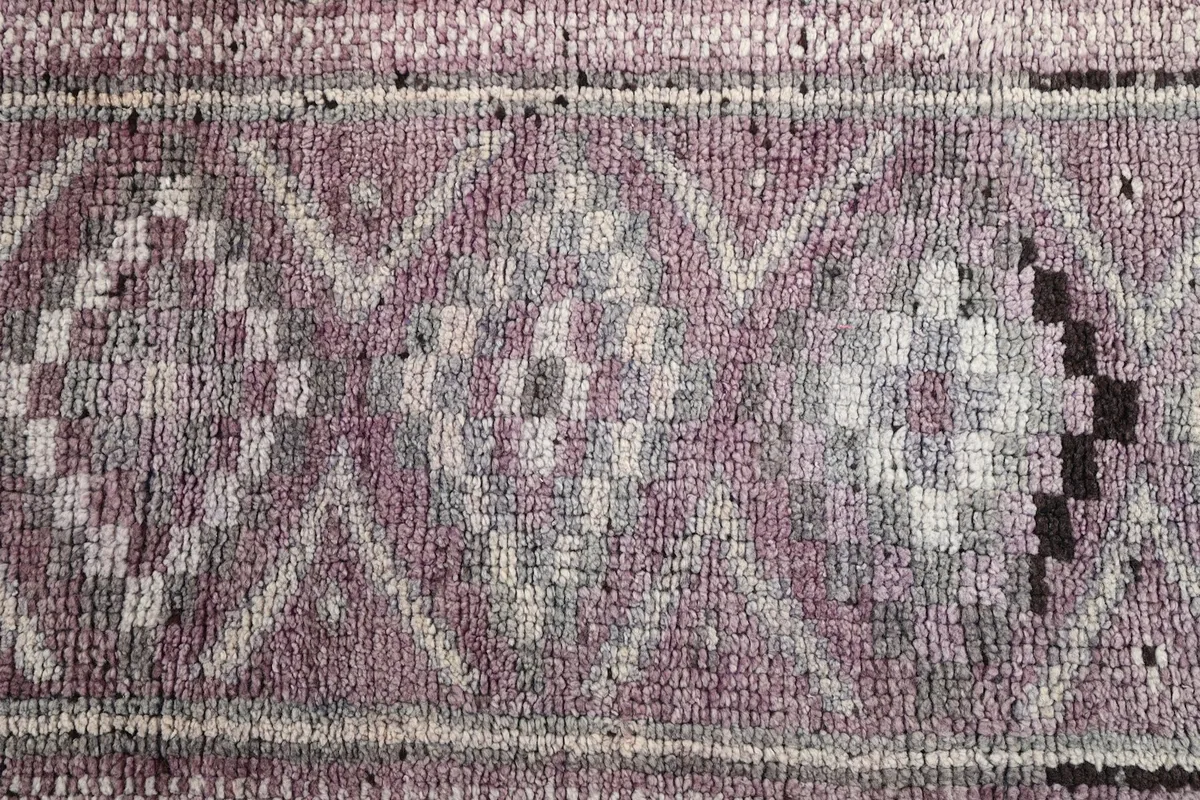 Overhead detail of the rug's central pattern, showcasing the intricate geometric design and varying shades of rose and gray.