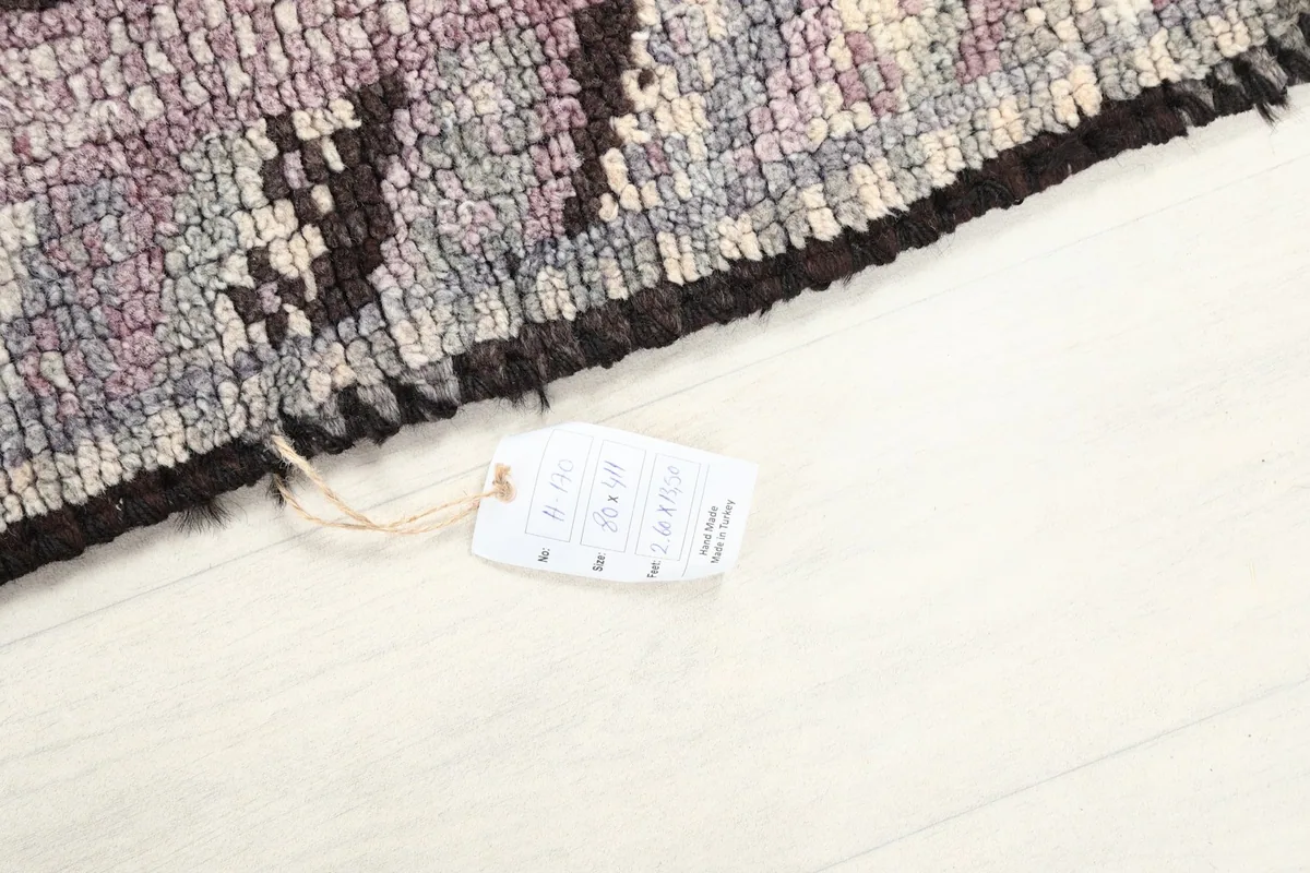 Corner of the rug with a product tag, indicating its size and origin, on a light floor.