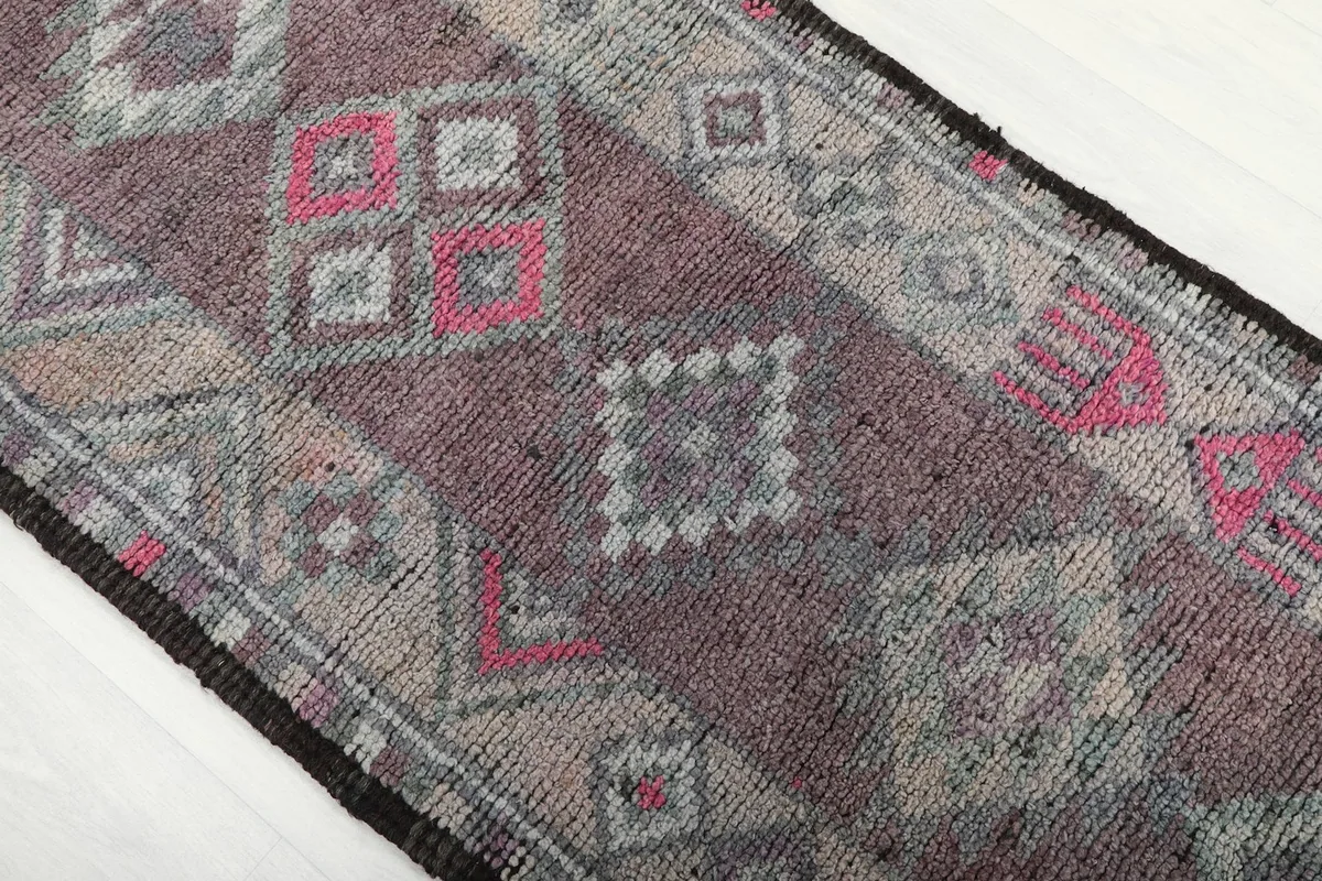 Mid-section detail of the runner rug, focusing on the rose, gray, and pink tribal motifs.