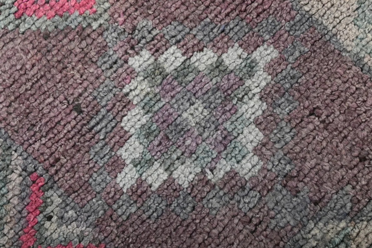 Macro shot of the rug's low wool pile, revealing the hand-knotted texture and color variations.