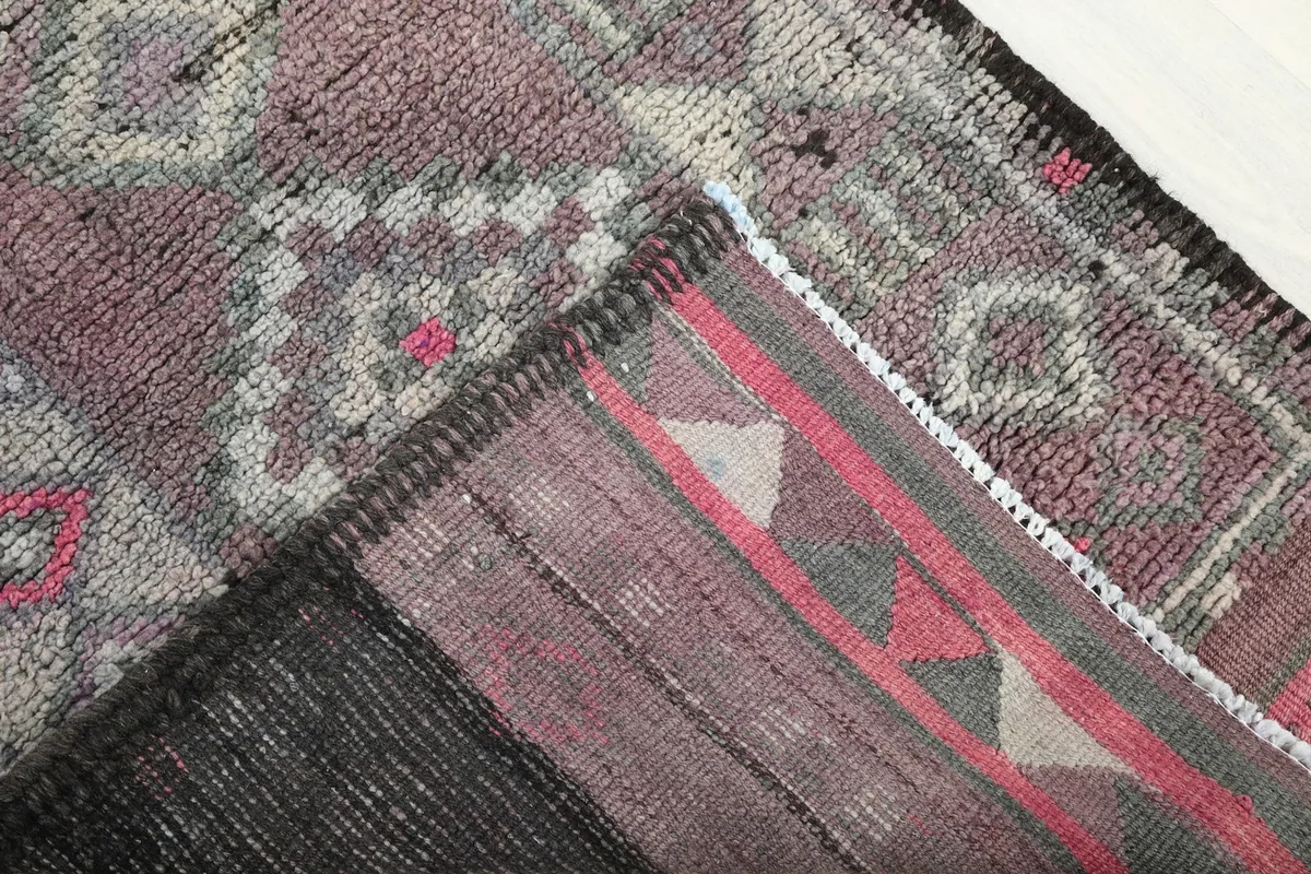 Partial view of the rug's reverse side and edge, showing the cotton foundation and hand-knotting.