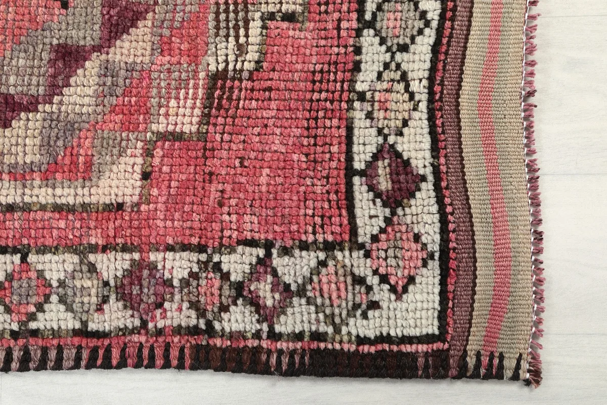Detail of the rug's border and fringe, showing the intricate knotting