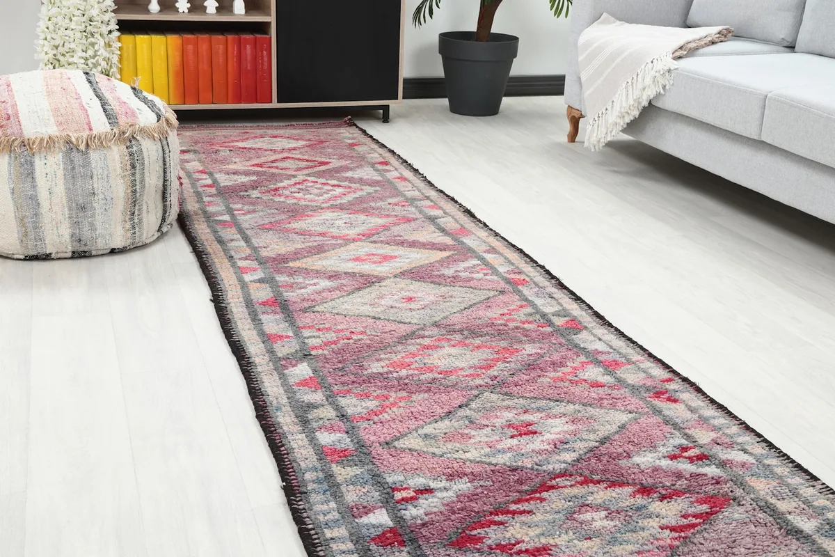 Close-up room view of the runner rug, highlighting the geometric patterns and colors near a striped pouf.