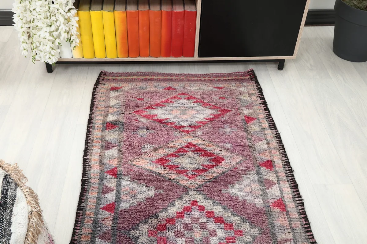 Overhead view of a section of the runner rug in a room, looking towards a colorful bookshelf.