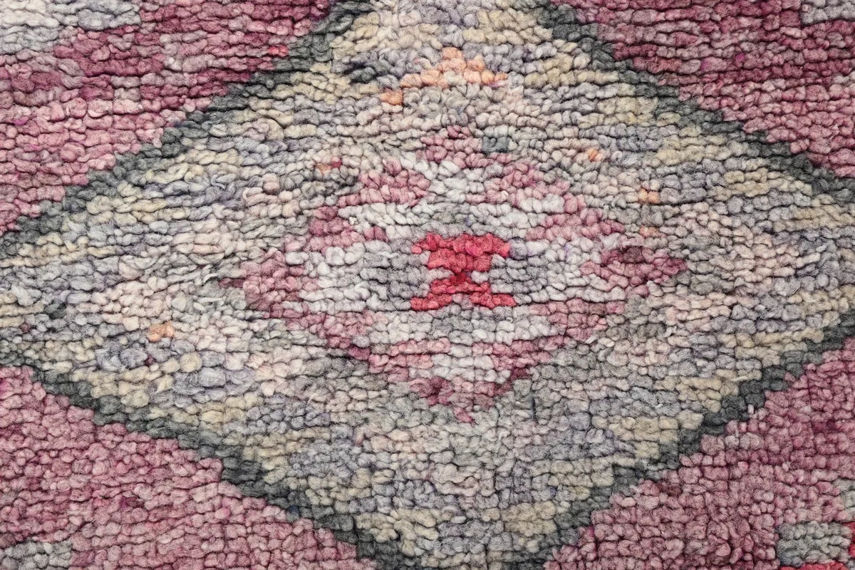 Macro shot of the wool pile texture and a central diamond motif, revealing subtle color variations.