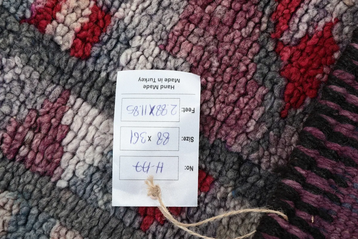 Label attached to the rug showing its dimensions in feet and centimeters, and indicating 'Hand Made in Turkey'.