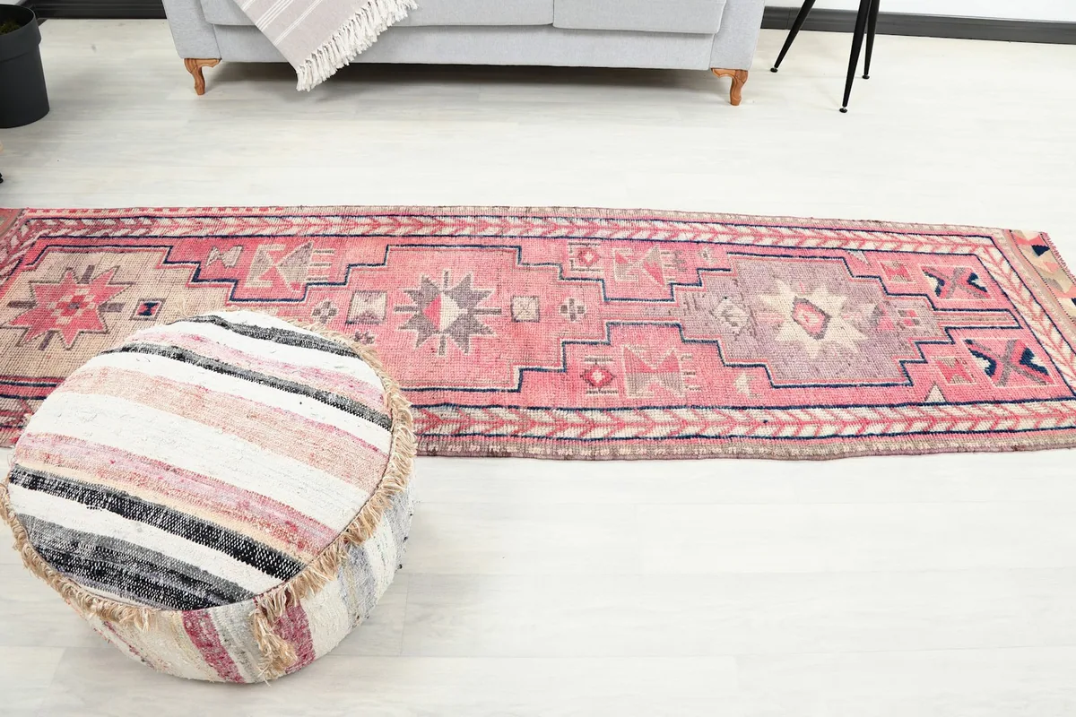 Overhead view of the full runner rug in a room, alongside a striped pouf