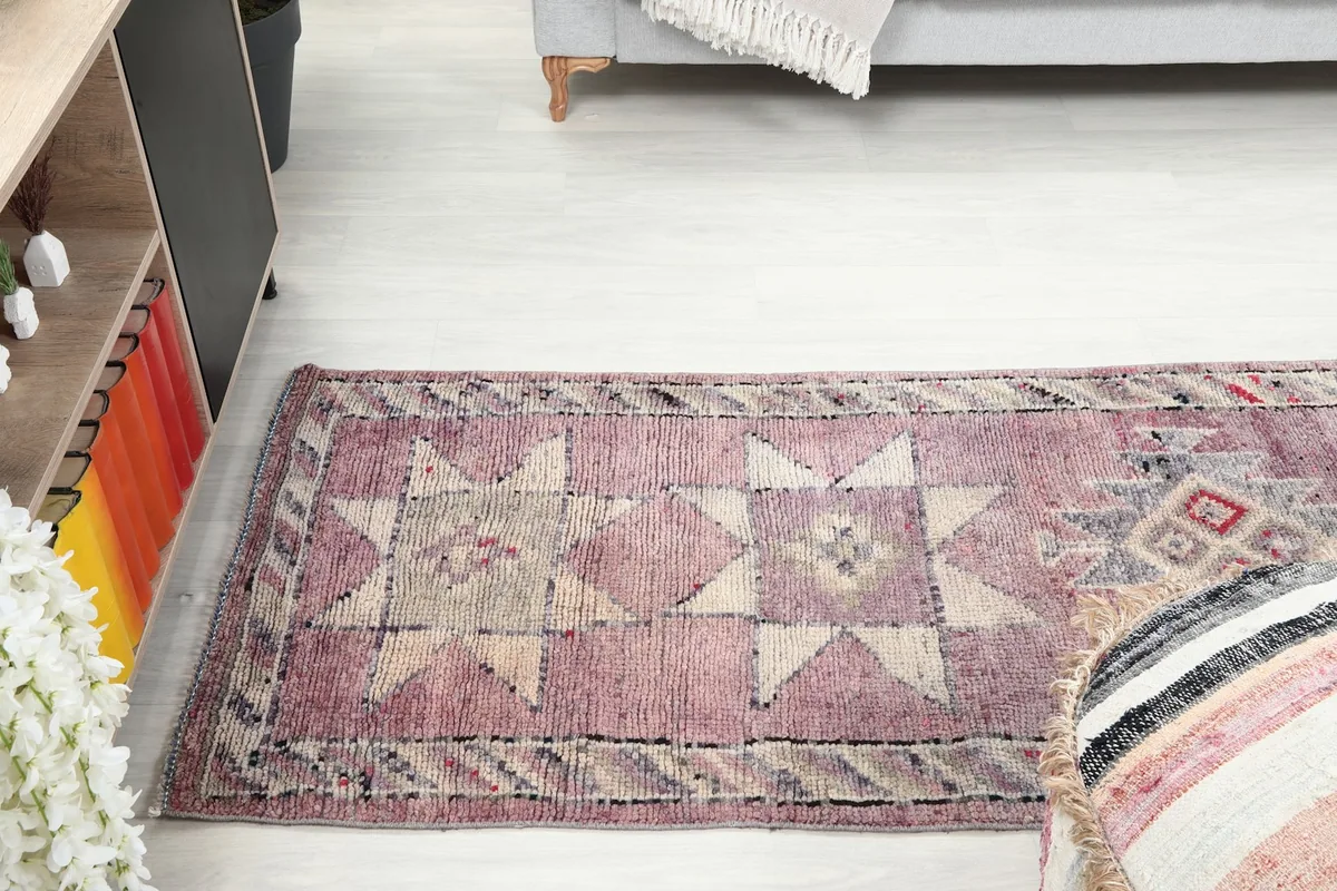 Runner rug extending into a living space, viewed from above a pouf