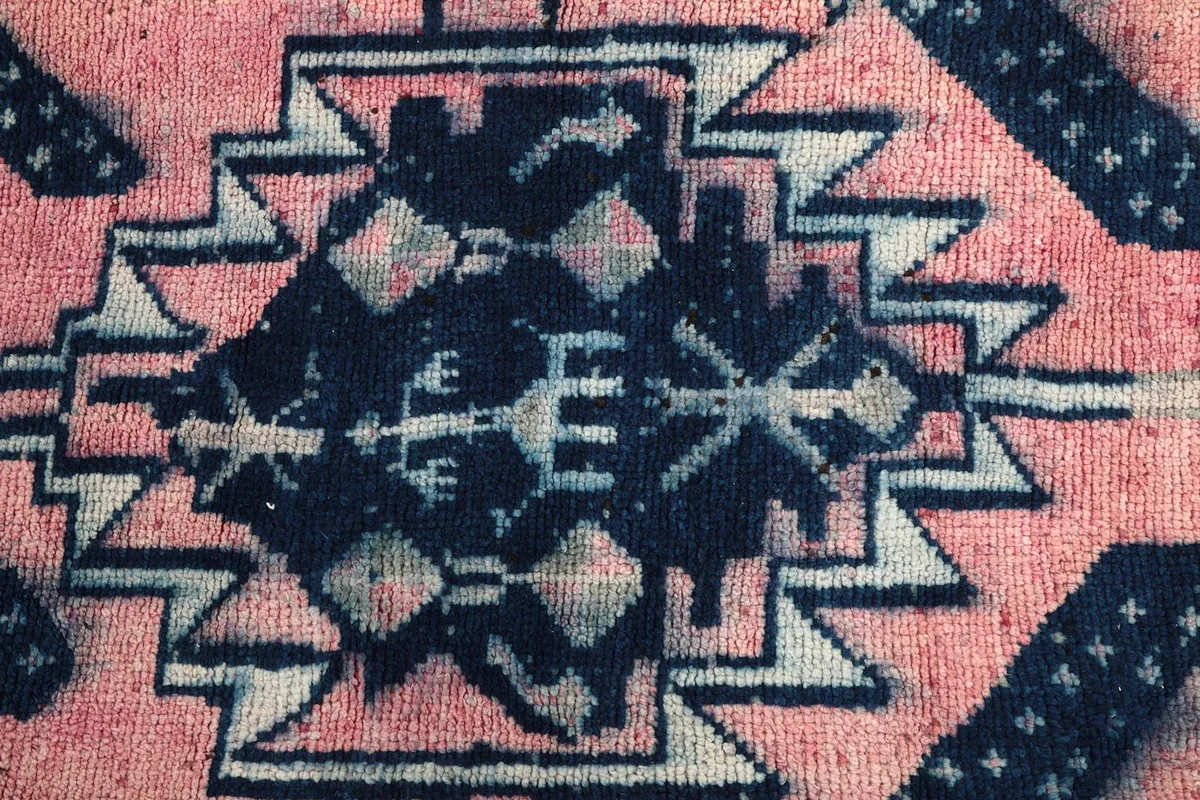 Zoomed-in detail of the hand-knotted wool pile, showing the texture and color variations of the central motif