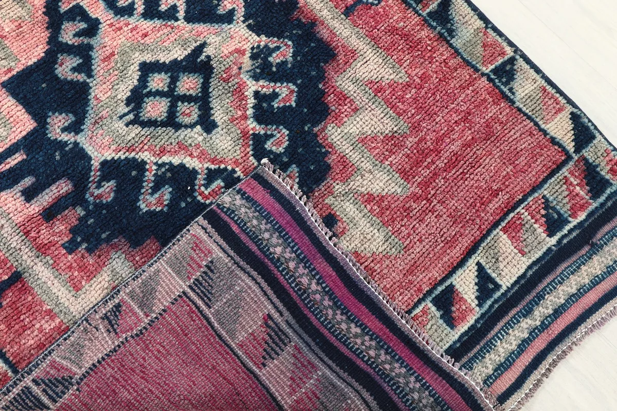 Corner of the rug folded to reveal the hand-knotted cotton foundation and the reverse side of the pile