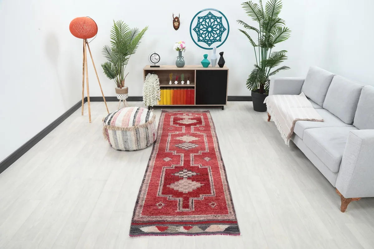 Vintage red runner rug placed in a modern living room setting with a gray couch