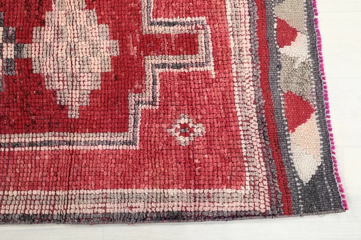 Detailed view of the rug's border and main field, highlighting the red and gray colors