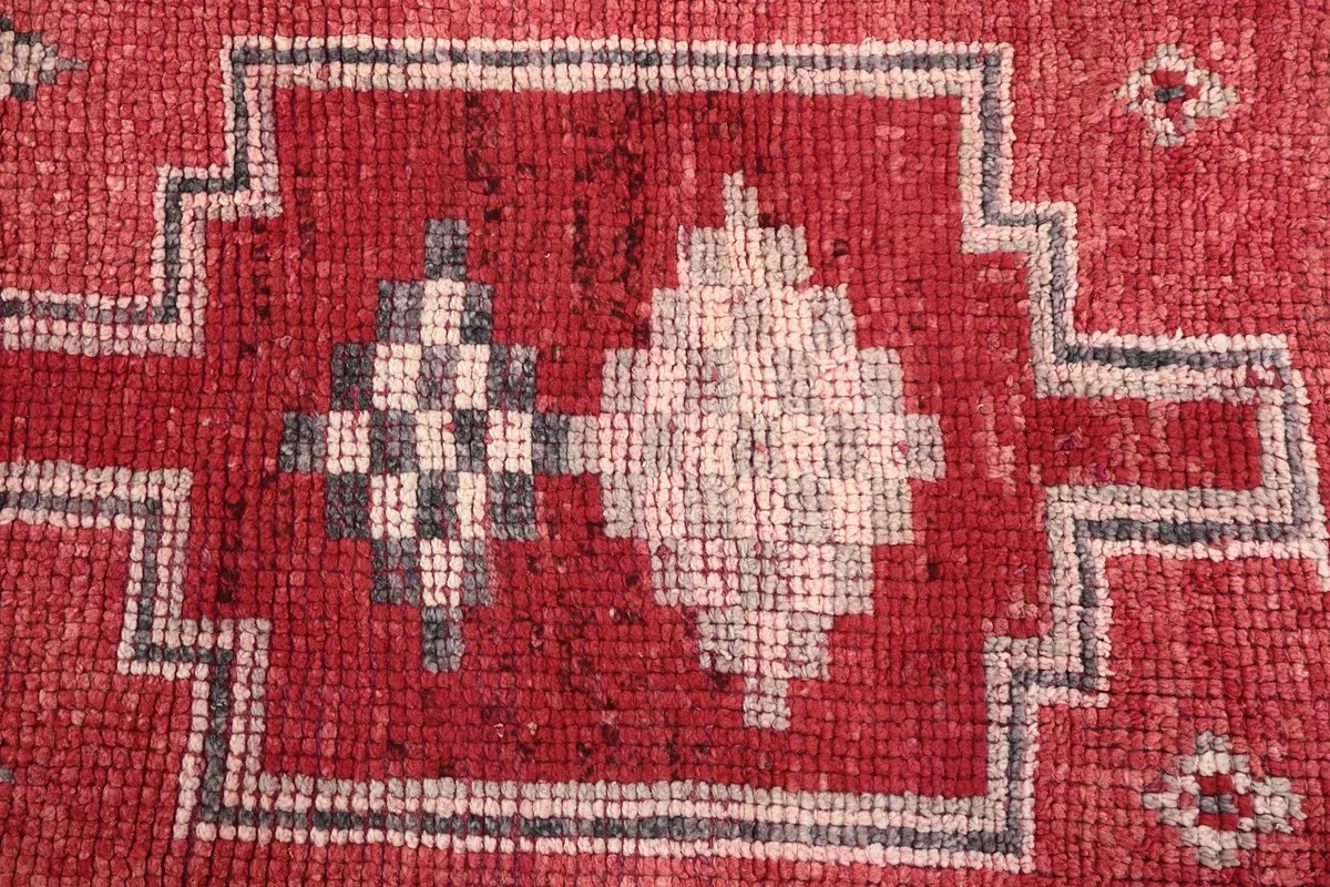Close-up of a central geometric motif on the red field with gray and ivory details