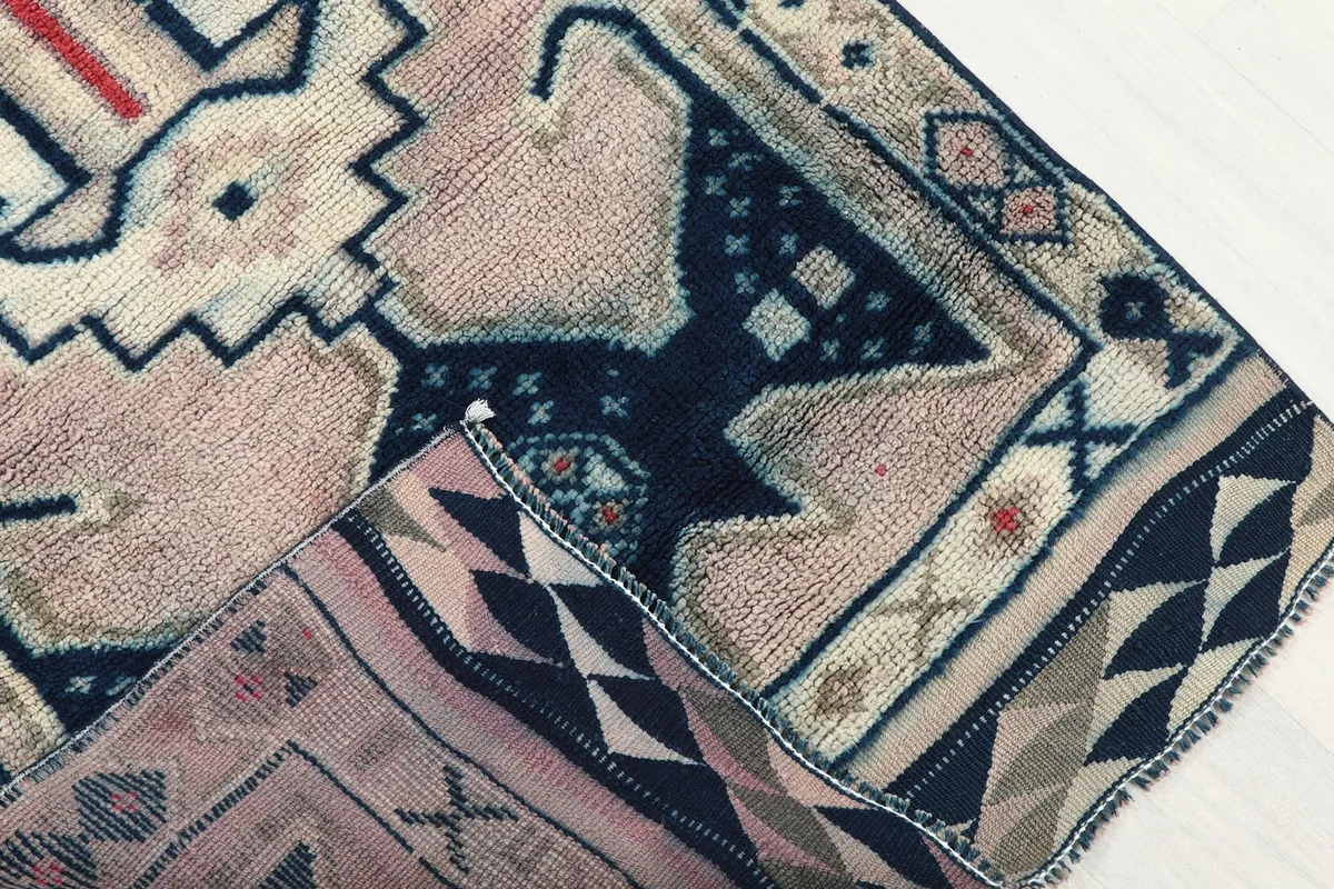 Folded corner of the rug revealing the cotton foundation and reverse side pattern