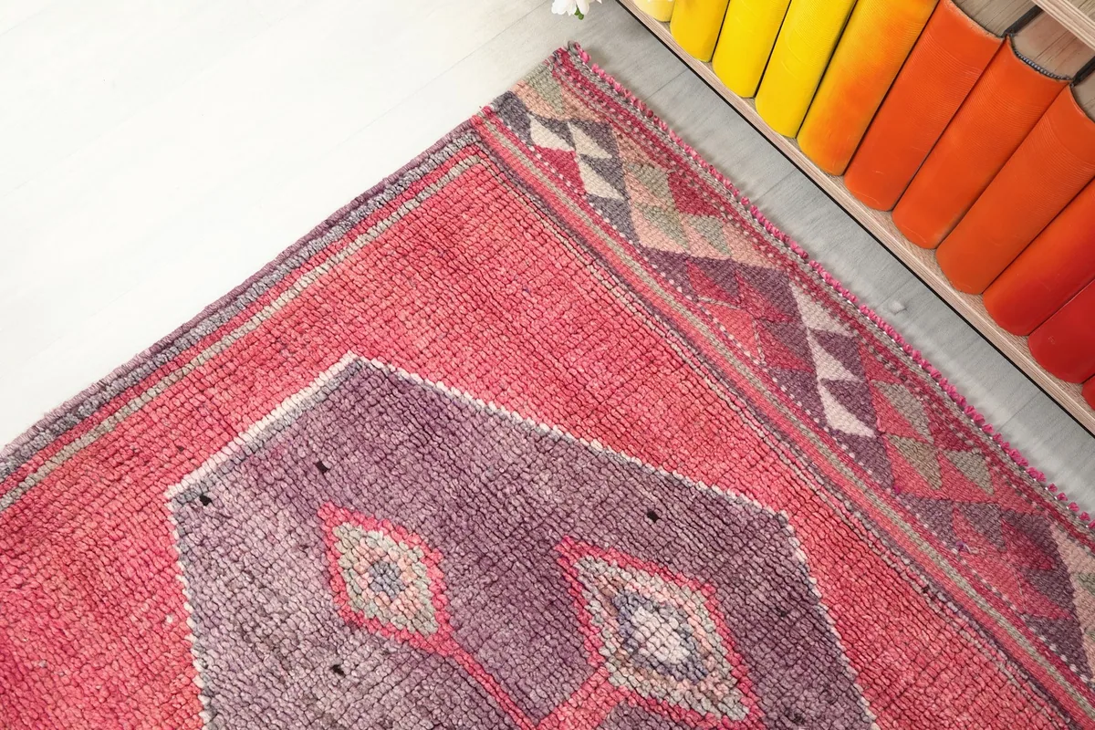Detail of the geometric border pattern alongside a purple medallion and the faded red field.
