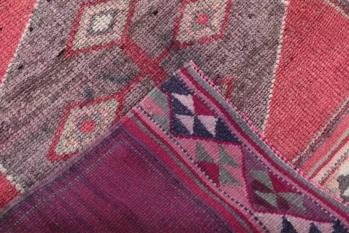 Corner of the rug folded to show the cotton foundation and the intricate backside of the knotting.