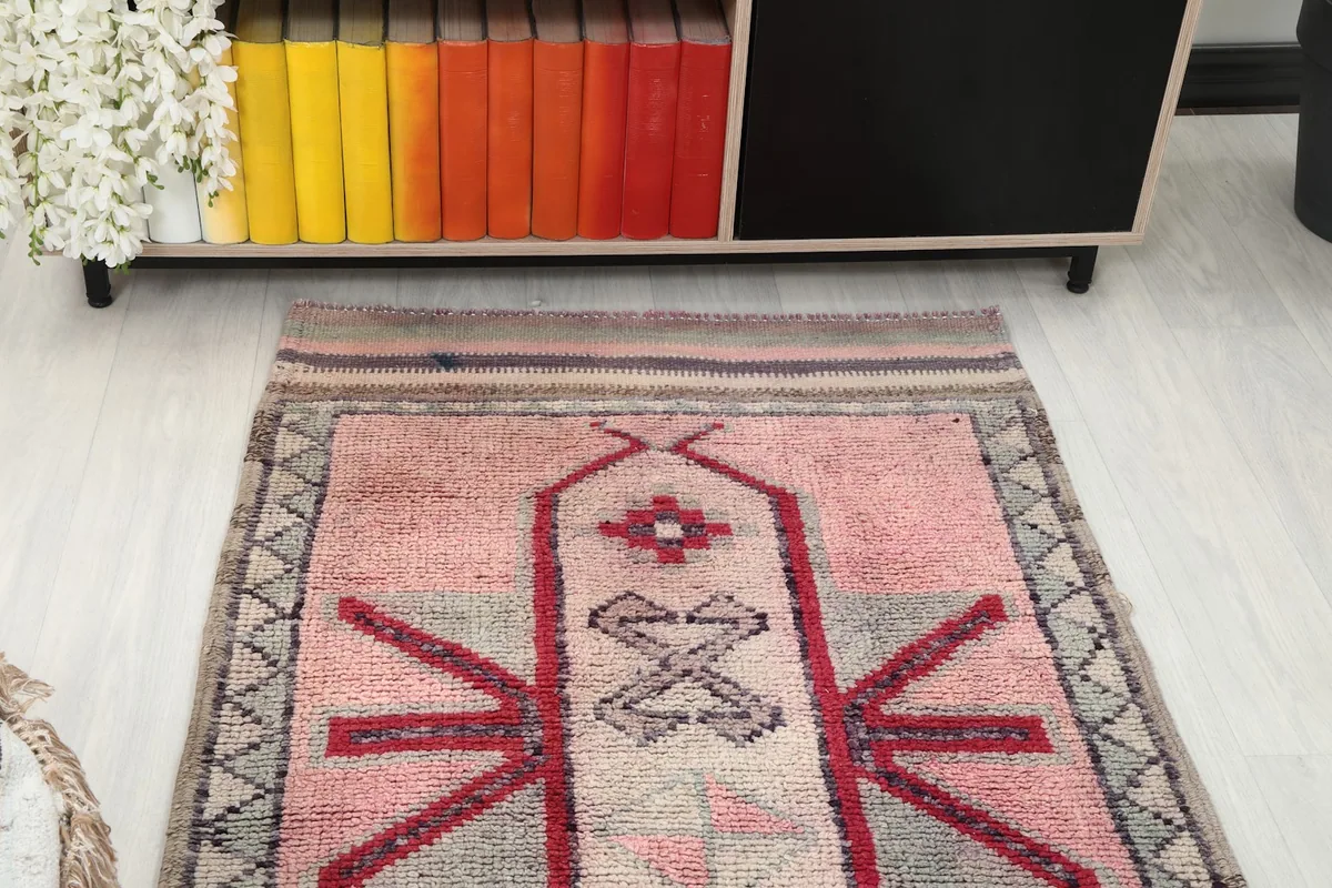 Overhead view of one end of the rose runner rug in a room setting near a bookshelf