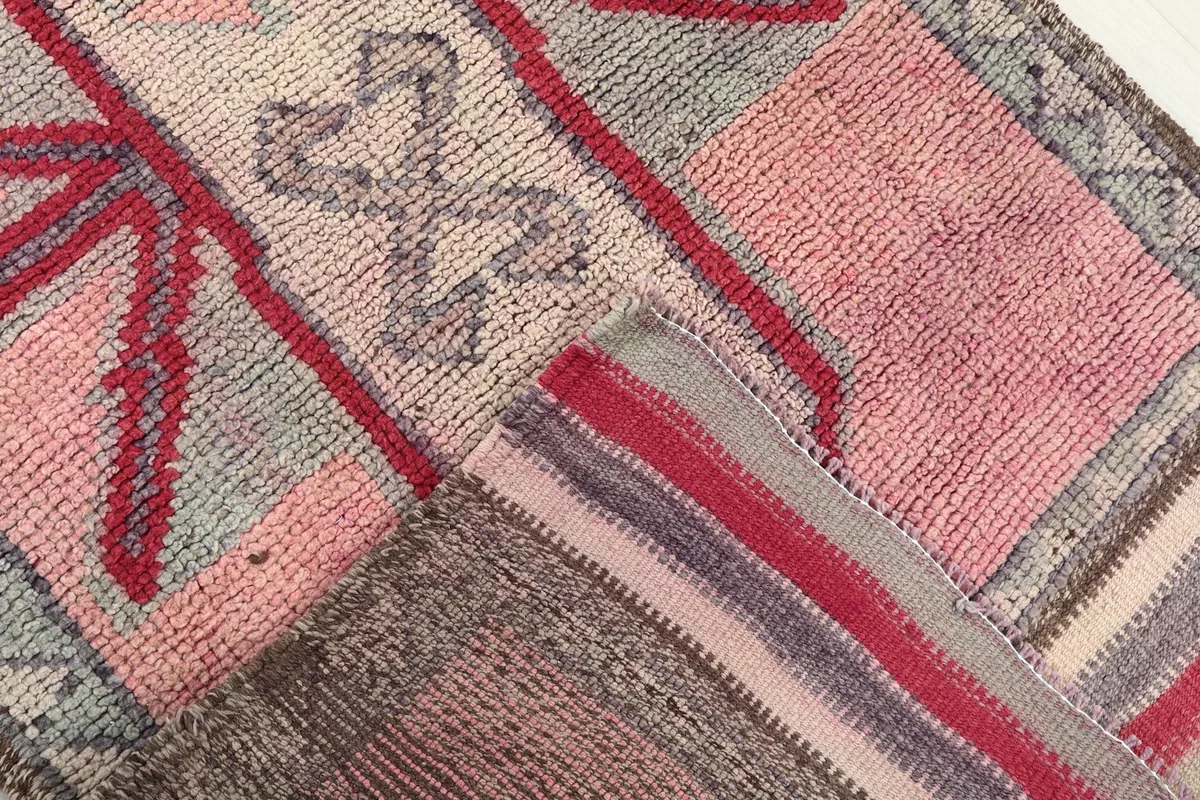 View of the rug's underside and folded edge, showing the cotton foundation and wool pile