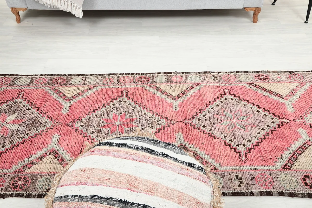 View from above the ottoman, looking down the length of the rose and gray vintage runner