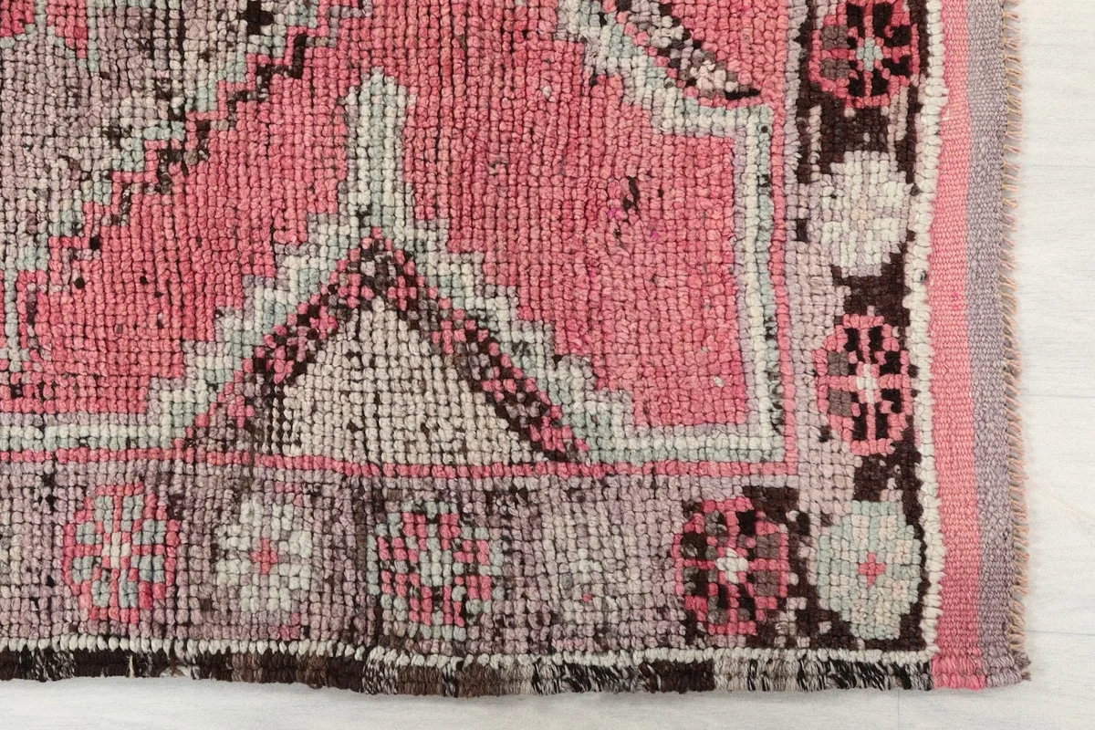 Detail of the rug's edge and border, highlighting the hand-knotted wool pile and color variations