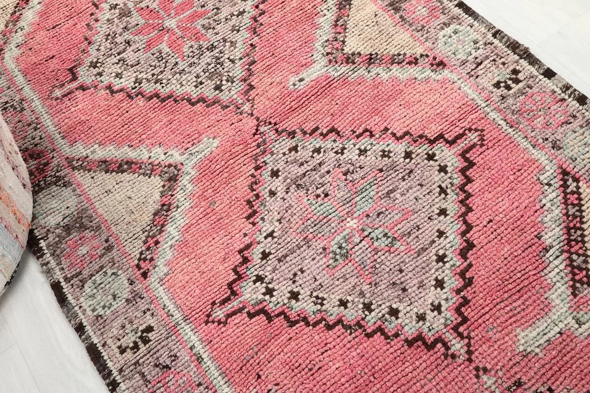 Close-up of a central geometric motif in shades of rose, beige, and gray with black accents